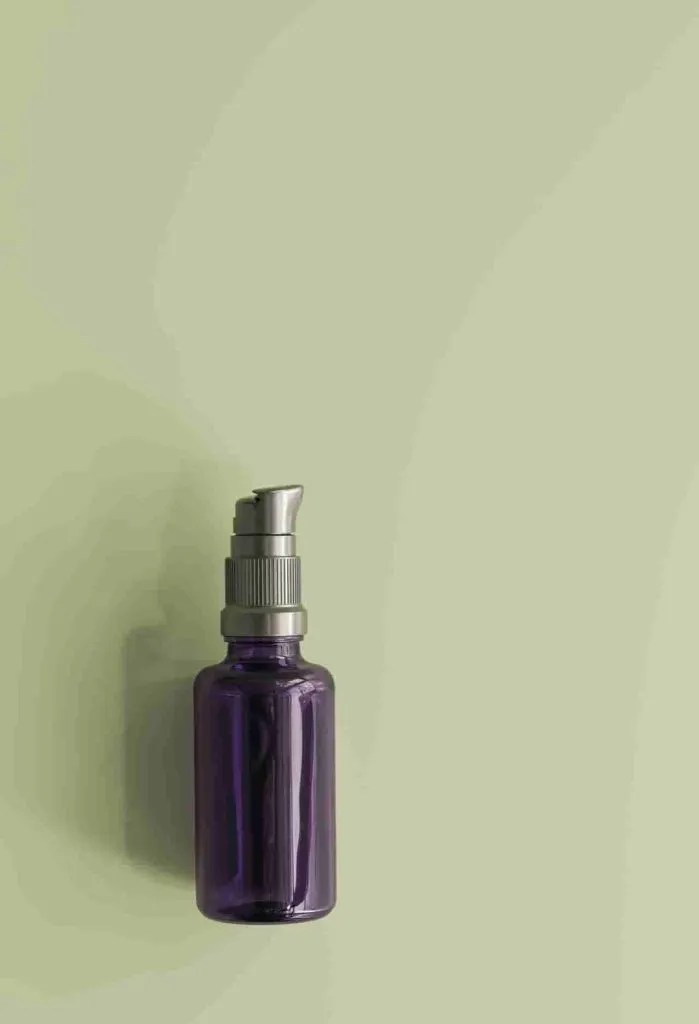 a dark purple glass bottle with pump